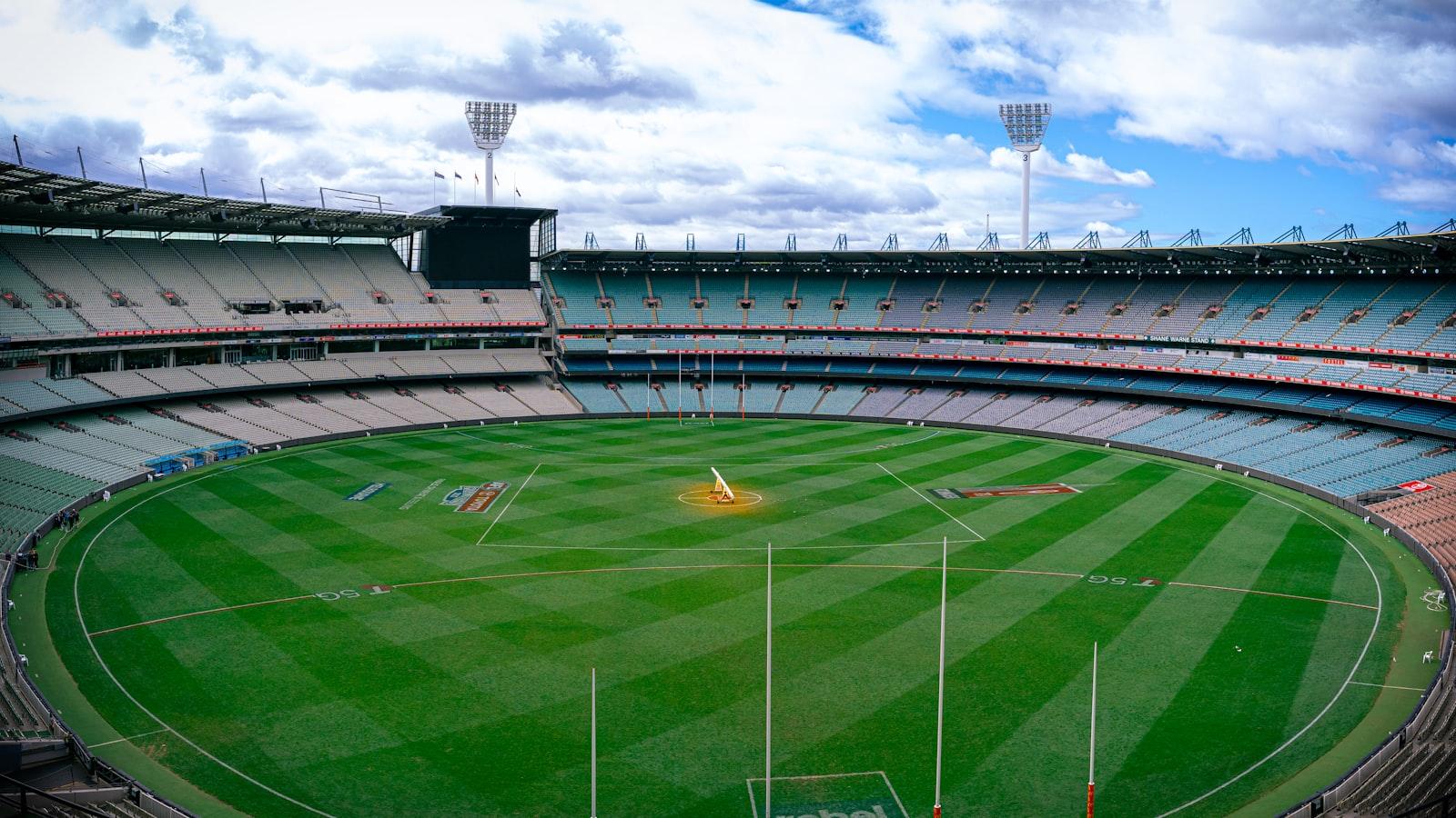 A Sports Stadium with a Field and a Field with a Crowd of People with Melbourne Cricket Ground in the Background
